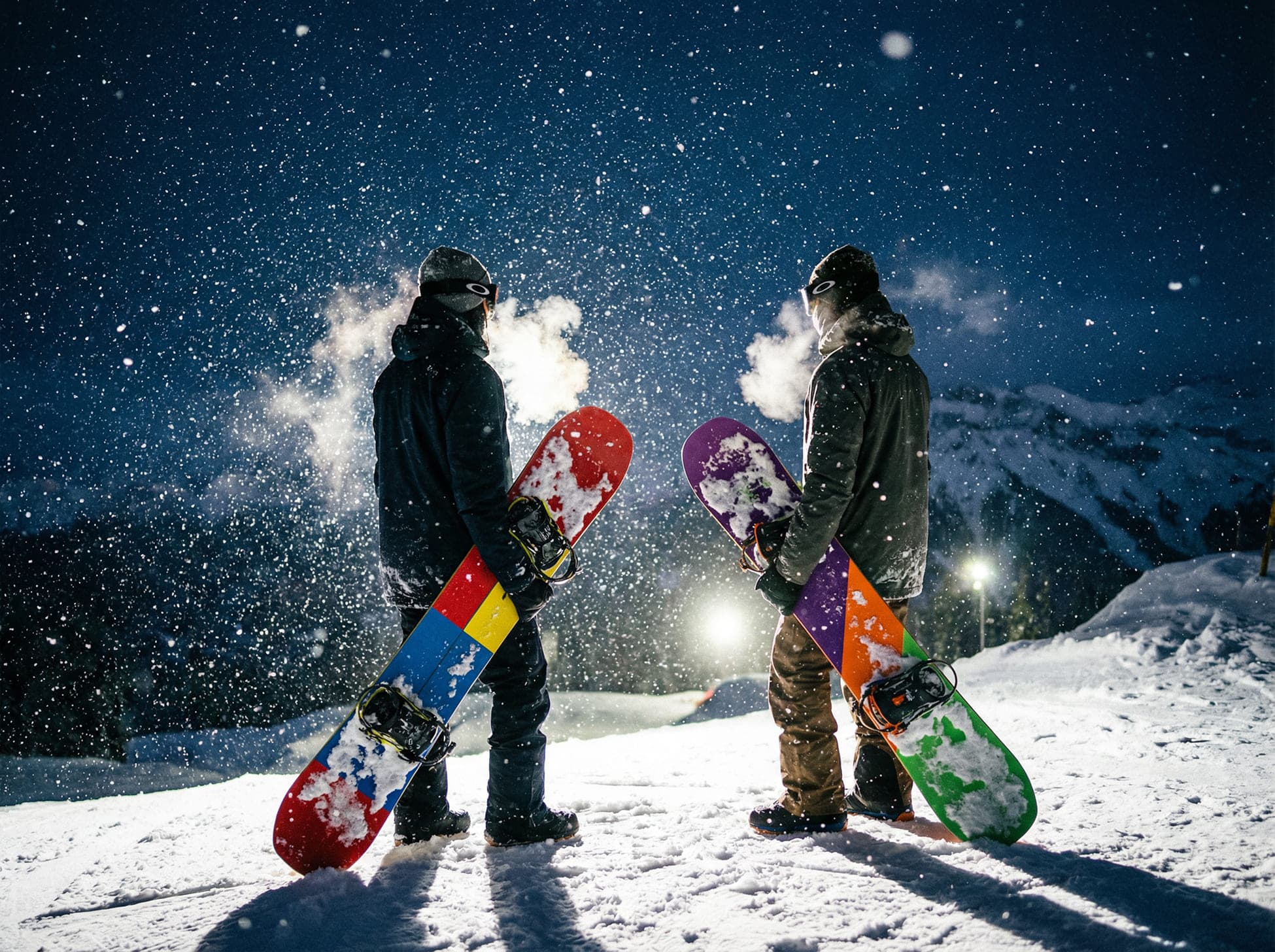 Two snowboarders beneath a snowfall at night, cinematic, 16:9